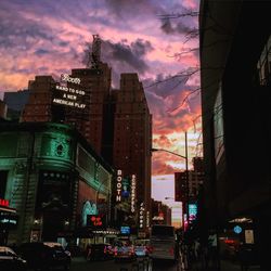 Traffic on city street against cloudy sky