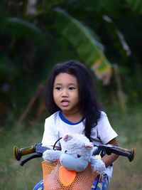 Cute girl looking away while riding bicycle in park