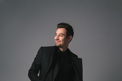 Young man looking away against gray background