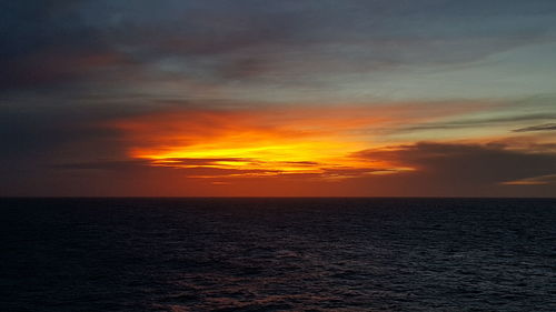 Scenic view of sea against dramatic sky during sunset