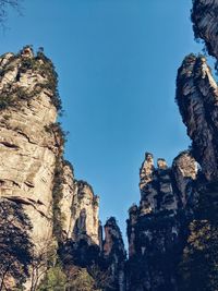 Low angle view of rocky mountains against clear blue sky