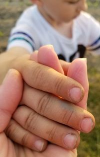 Cropped image of person holding boy hand