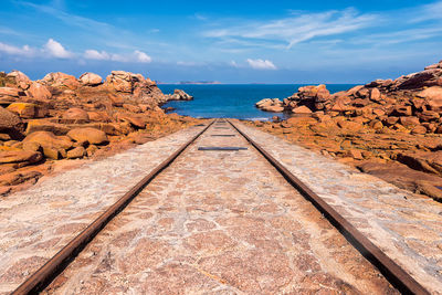 Scenic view of old boats launching rail with red rocks against blue sky in brittany, france