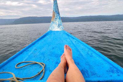 Low section of woman relaxing in boat on lake