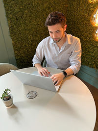 High angle view of young man using phone while sitting on table