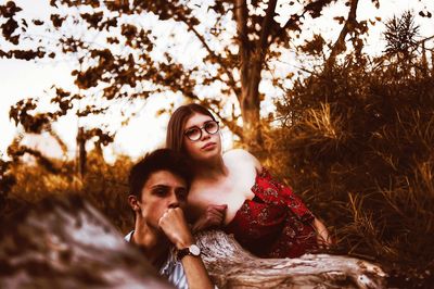 Portrait of couple leaning against tree trunk