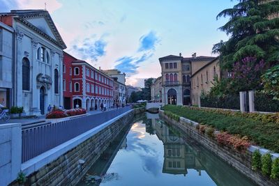 Canal amidst buildings in city against sky