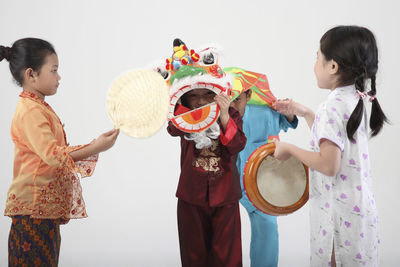 Girls by boys wearing costume against white background