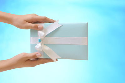 Midsection of person holding paper against blue sky