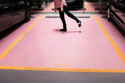 Low section of woman standing by cars at parking log