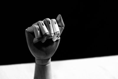 Close-up of hand on table against black background