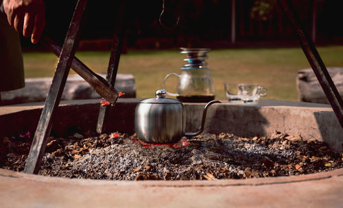 Man making drip coffee with kettle on charcoal stove at camping.