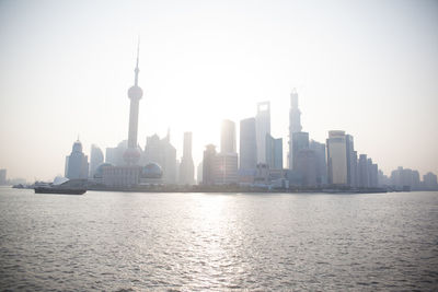 Huangpu river in front of oriental pearl tower amidst buildings in city against clear sky