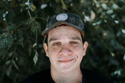 Close-up portrait of smiling young man against plants