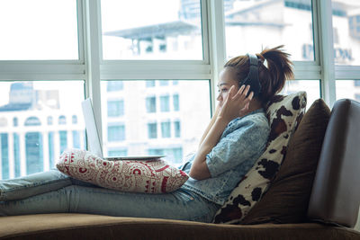 Side view of woman sitting on sofa at home