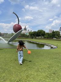 Rear view of woman standing on field against sky