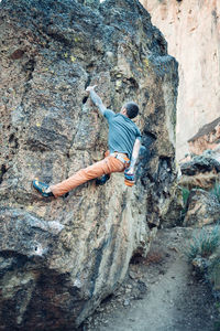 Male climber getting to the top of the boulder in smith rock park