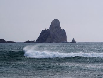 Scenic view of rocks in sea against clear sky