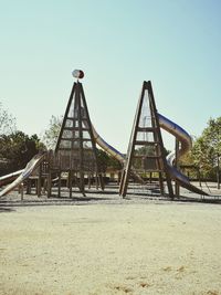 View of playground against clear blue sky in park