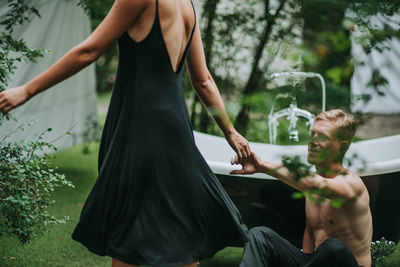 Midsection of man holding woman standing by plants