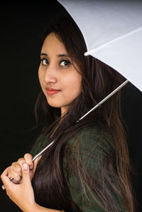 Close-up portrait of young woman against black background