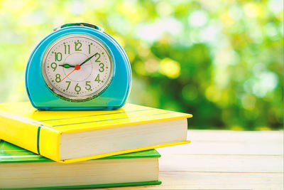 Close-up of clock on stacked books on table