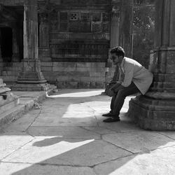 Man sitting on column by historical temple