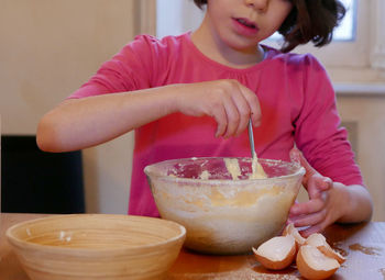 Midsection of girl mixing food in bowl at home