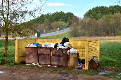 Man by garbage on field against trees