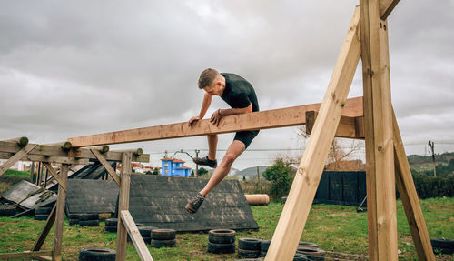 Man jumping on wood against sky