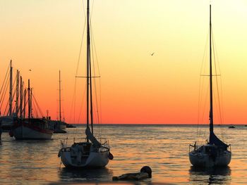 Sailboats in sea at sunset
