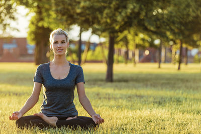 Full length of woman doing yoga on grass 