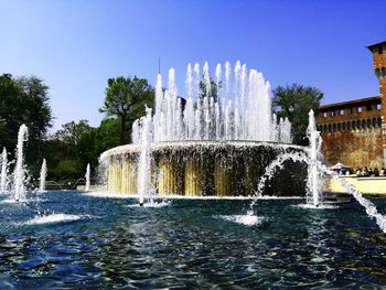 Fountain in front of built structure against clear sky