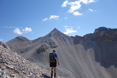Rear view of hiker on mountain against sky
