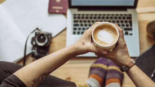 Close-up of woman holding coffee cup on table