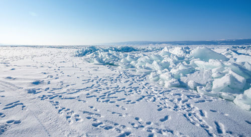 Scenic view of snow covered land against blue sky