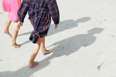 Low section of girls walking on sand