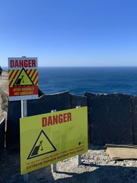 Information sign by sea against clear sky