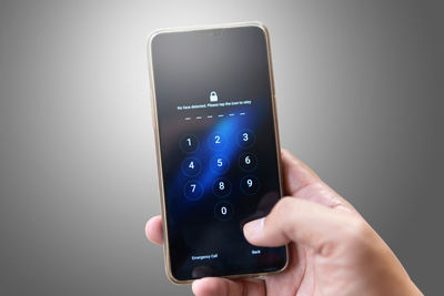 Close-up of hand holding mobile phone over white background