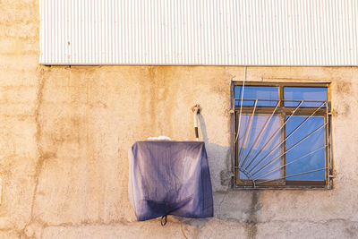 Cement wall of residence building with cooler engine and vintage wooden window frame with metal 