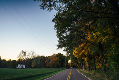 Road amidst trees against sky during autumn