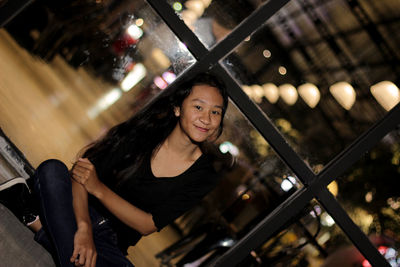 Portrait of woman sitting in illuminated shop