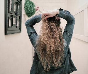 Rear view of woman with brown hair wearing flowers at home