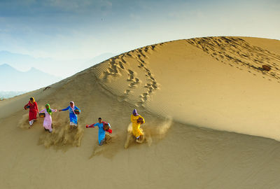 People enjoying in desert against sky