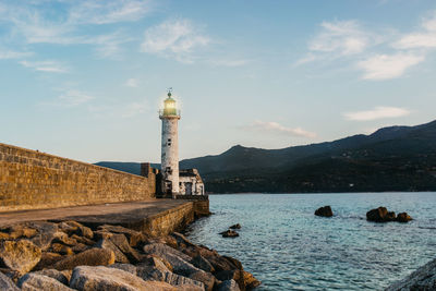 Lighthouse by sea against sky