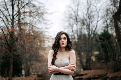 Portrait of young woman standing against bare trees