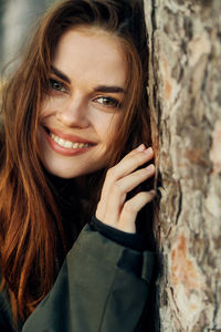 Portrait of smiling young woman with tree trunk