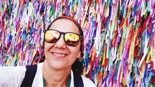 Portrait of smiling woman wearing sunglasses against multi colored bands