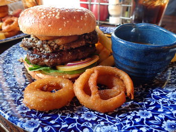 Close-up of burger by onion rings on table