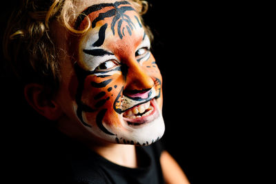 Close-up of boy with face paint against black background